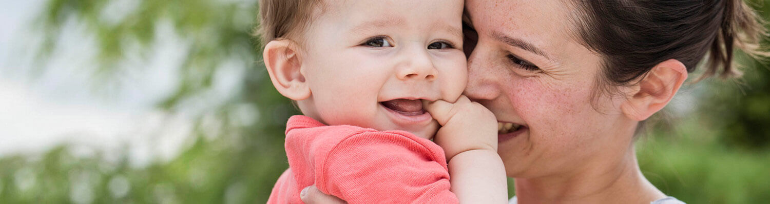 A woman lovingly holds a baby close to her face.