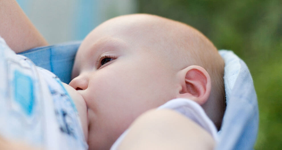 A close-up of a baby's face, partially obscured by a cloth, with a blurred background.