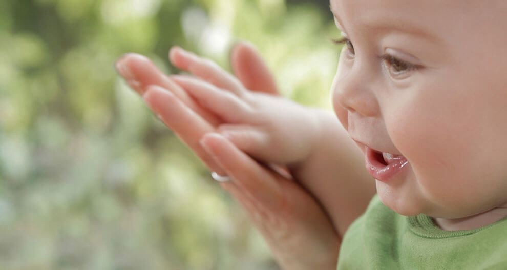 A close-up of a baby's face, with a blurred background, capturing a moment of curiosity or wonder.
