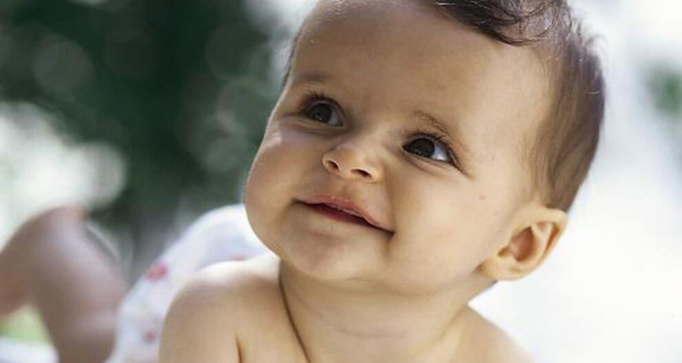 A baby with a curious expression is looking upwards.