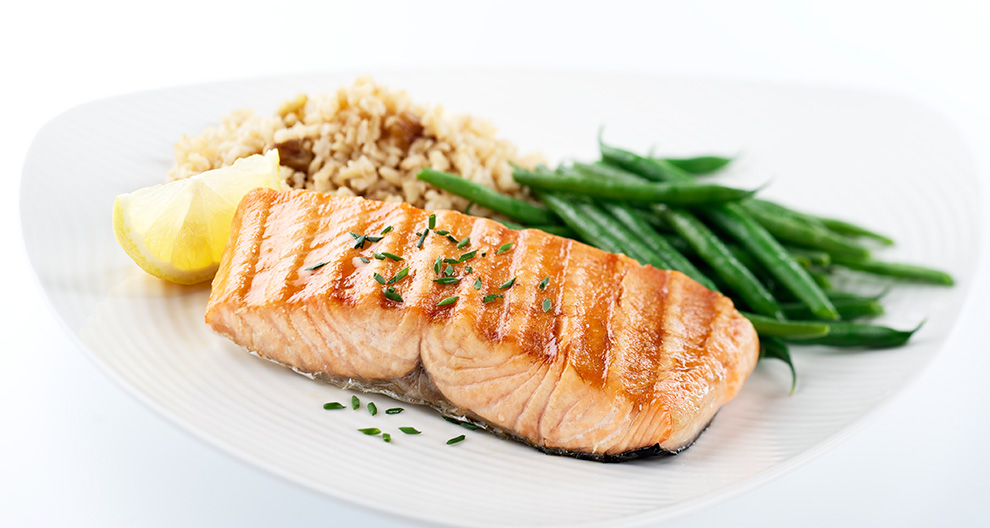Salmon fillet, rice, green beans, lemon wedge, and parsley garnish.