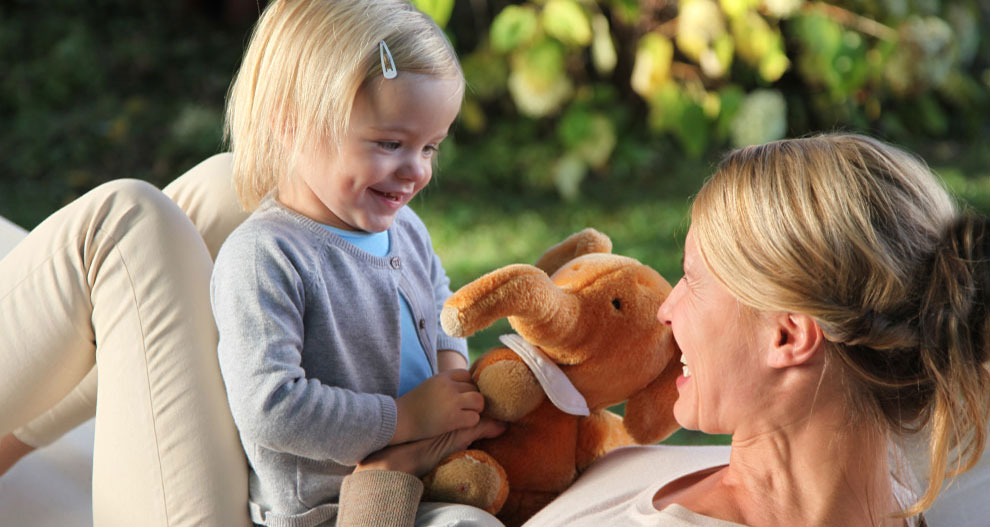 A child and an adult share a joyful moment outdoors.